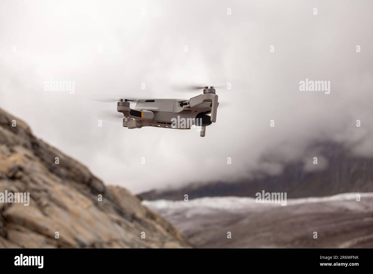 Eine Drohne schwingt anmutig in den wolkigen Himmel und fängt atemberaubende Blicke auf majestätische Berge im Hintergrund ein Stockfoto