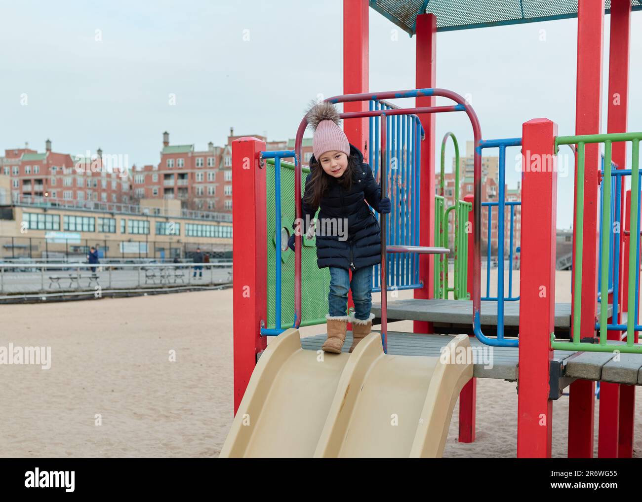 Ein junges Mädchen, das auf einem Spielplatz am Strand spielt Stockfoto