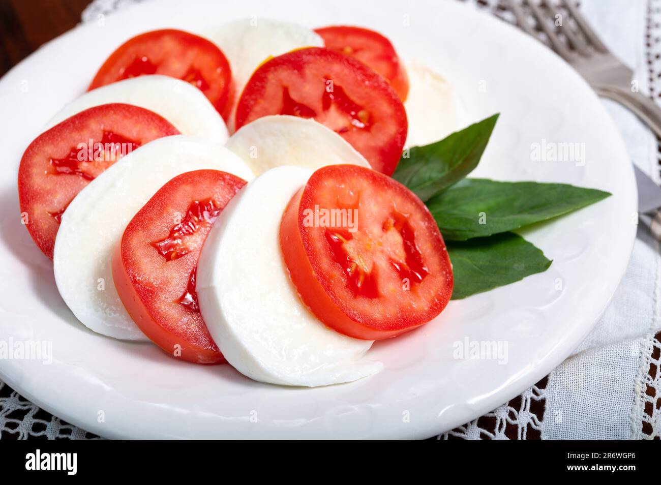 Itaianische vegetarische Speisen, frischer Caprese-Salat mit weißem, weichem italienischen Mozzarella-Käse, rote Tomaten und grünes Basilikum mit Olivenöl. Stockfoto