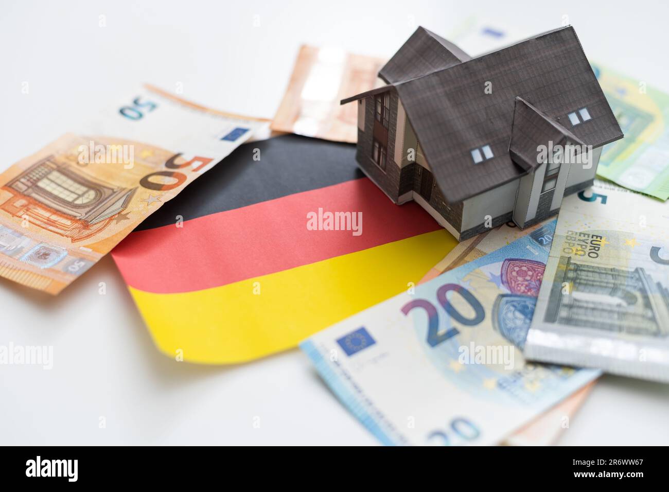 Immobilienkonzept. Auf der Flagge Deutschlands gibt es ein Modell eines Holzhauses mit der Inschrift - ZINSSATZ PRIME Stockfoto
