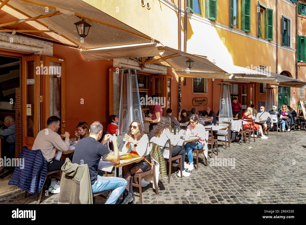 Im Tonnarello, einem beliebten Restaurant in Trastevere, Rom, können Gäste im Sonnenschein speisen Stockfoto