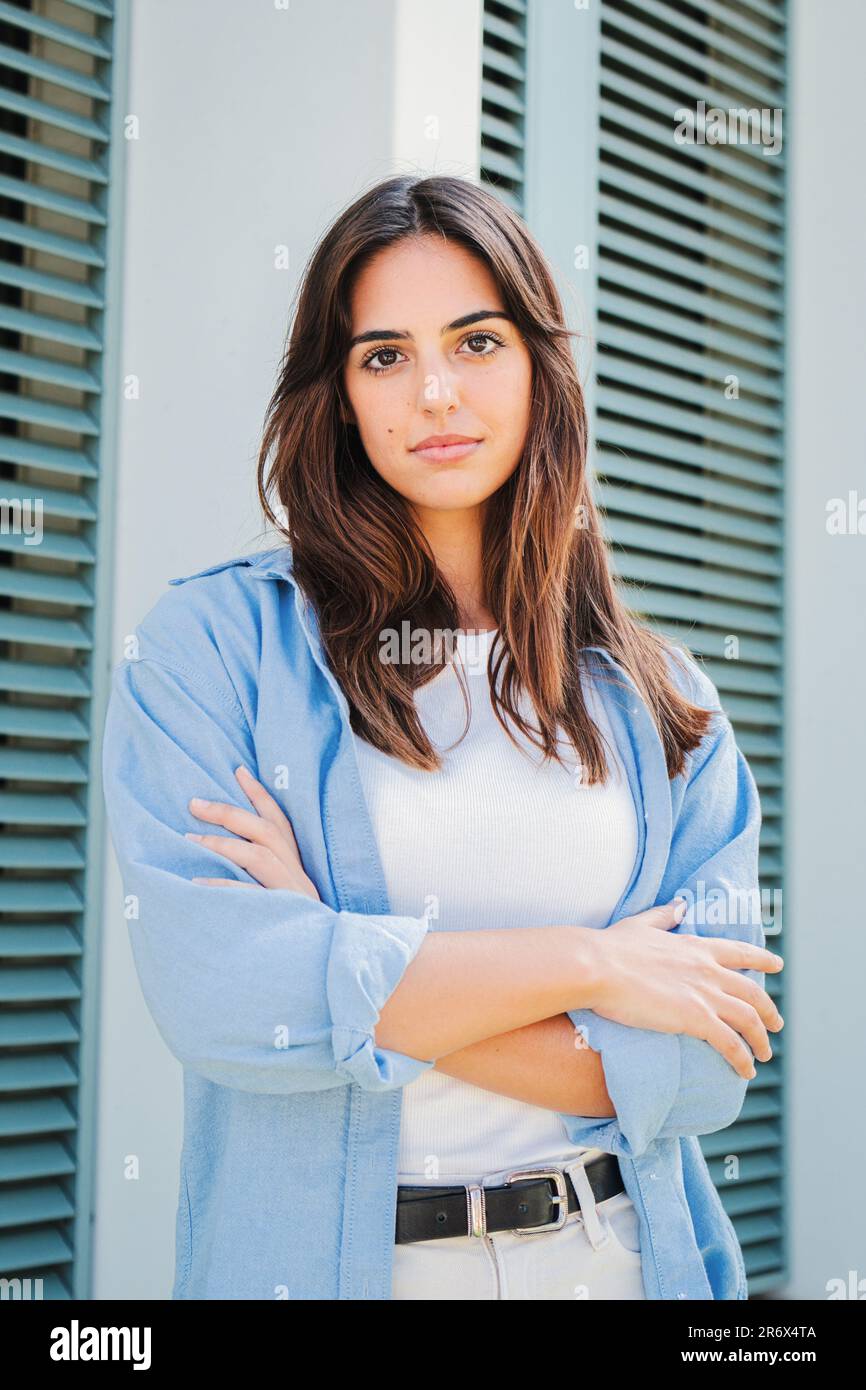 Vertikales Porträt einer nachdenklichen Teenagerin mit selbstbewusster Gesichtsausdruck-Pose. Kaukasische, seriöse, junge Studentin mit verschränkten Armen, die nachdenklich vor der Kamera in lässiger Kleidung im Freien steht. . Hochwertiges Foto Stockfoto