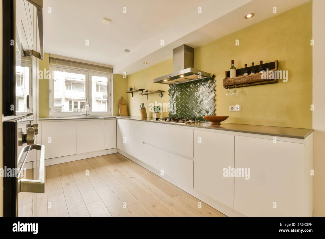 Eine Küche mit gelben Wänden und Holzfußboden in der Mitte des Zimmers, es gibt einen Ofen an der Wand Stockfoto