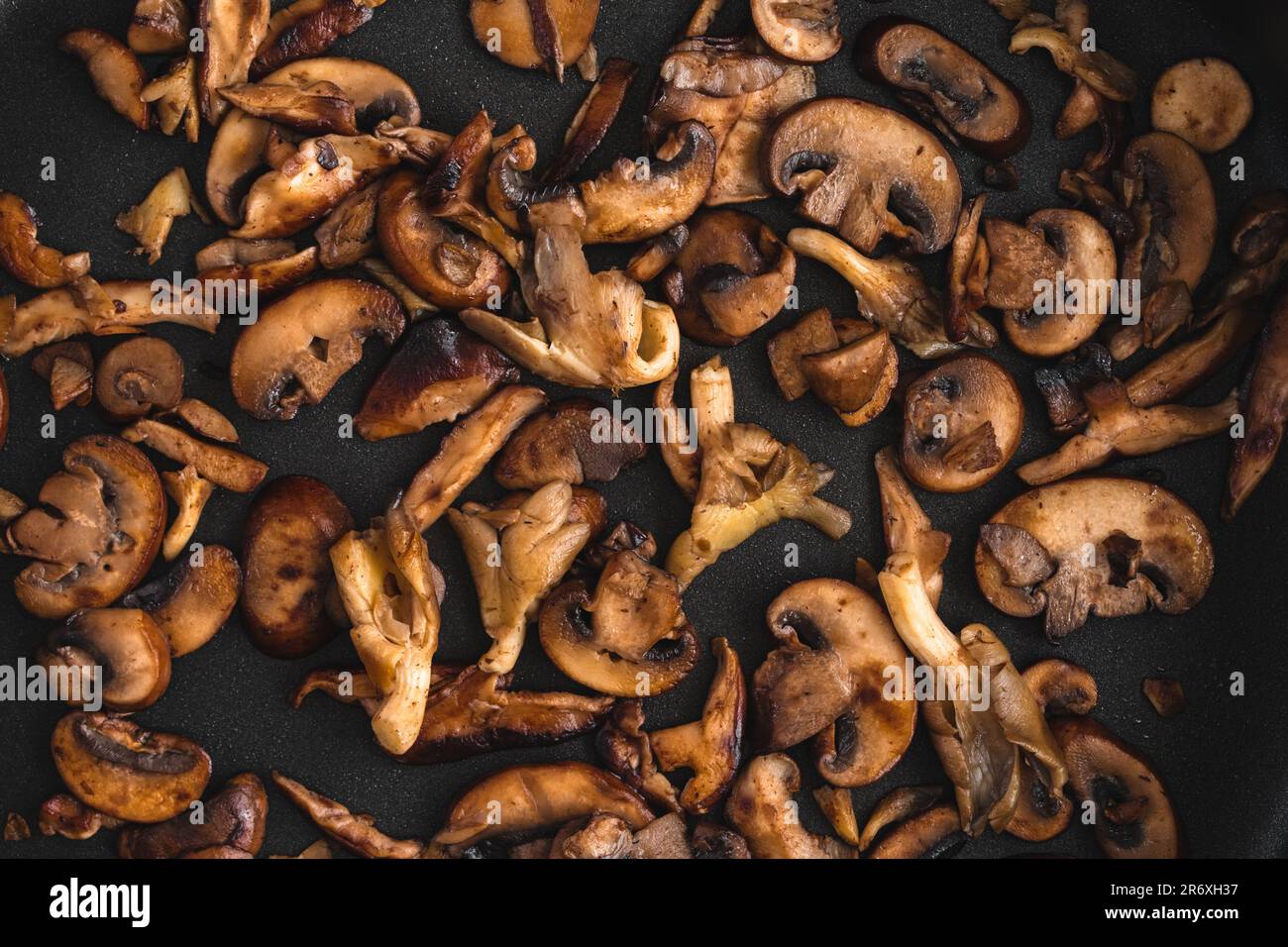 Brawned Wild Mushroom s Nahaufnahme in einer antihaftbeschichteten Sautenpfanne von oben: Blick von oben auf Austern, Shiitake und Krimini-Pilze in Butter gekocht Stockfoto