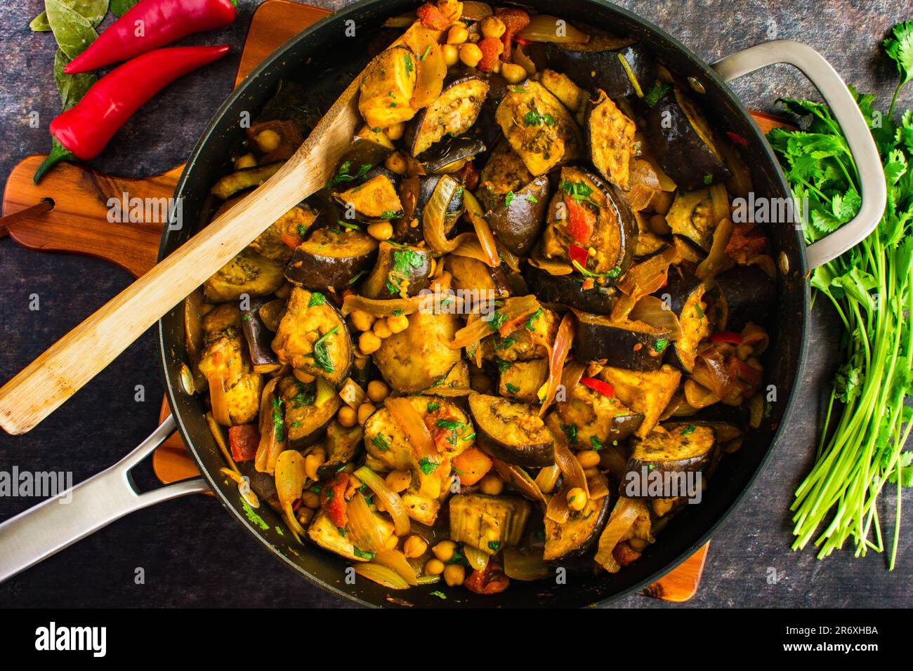 Vegane geröstete Auberginen- und Kichererbsen-Curry serviert in einer Pfanne: Auberginen-Curry mit Garbanzo-Bohnen, Tomaten, Zwiebeln und Koriander Stockfoto
