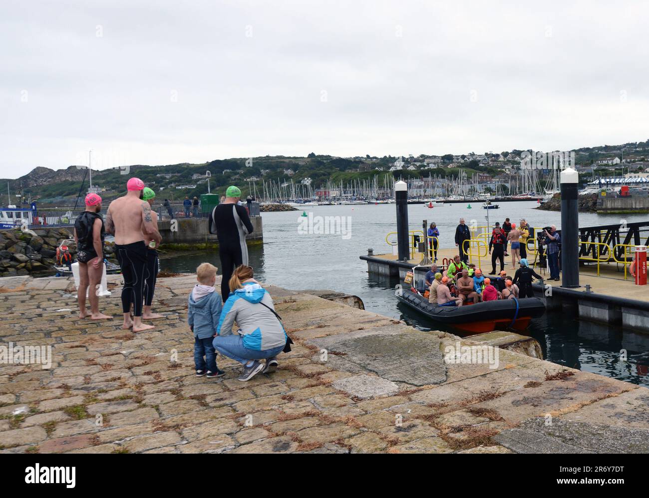 Die Teilnehmer eines Schwimmwettbewerbs gehen auf Boote, die sie zum Ausgangspunkt bringen. Dublin Bay, Irland. Stockfoto