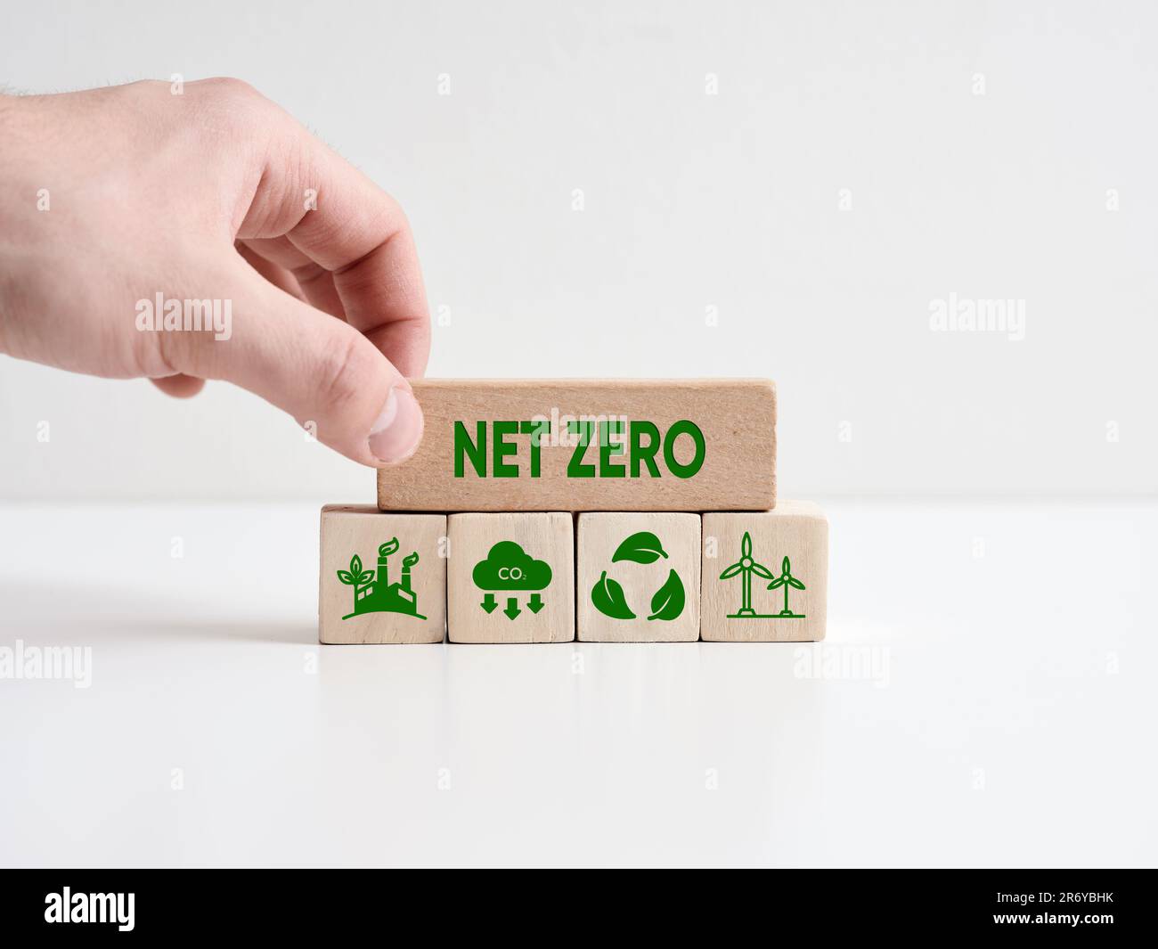 Netto-Null- und CO2-neutrales Konzept. Nettoziel für keine Treibhausgasemissionen. Mit der Hand wird ein Holzblock mit dem Wort net zero mit Umweltschutz platziert Stockfoto