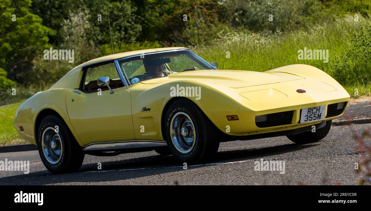 Stony Stratford, Großbritannien - Juni 4. 2023: 1974 gelbe GENERAL MOTORS CHEVROLET CORVETTE STINGRAY Klassiker, die auf einer englischen Landstraße fahren. Stockfoto