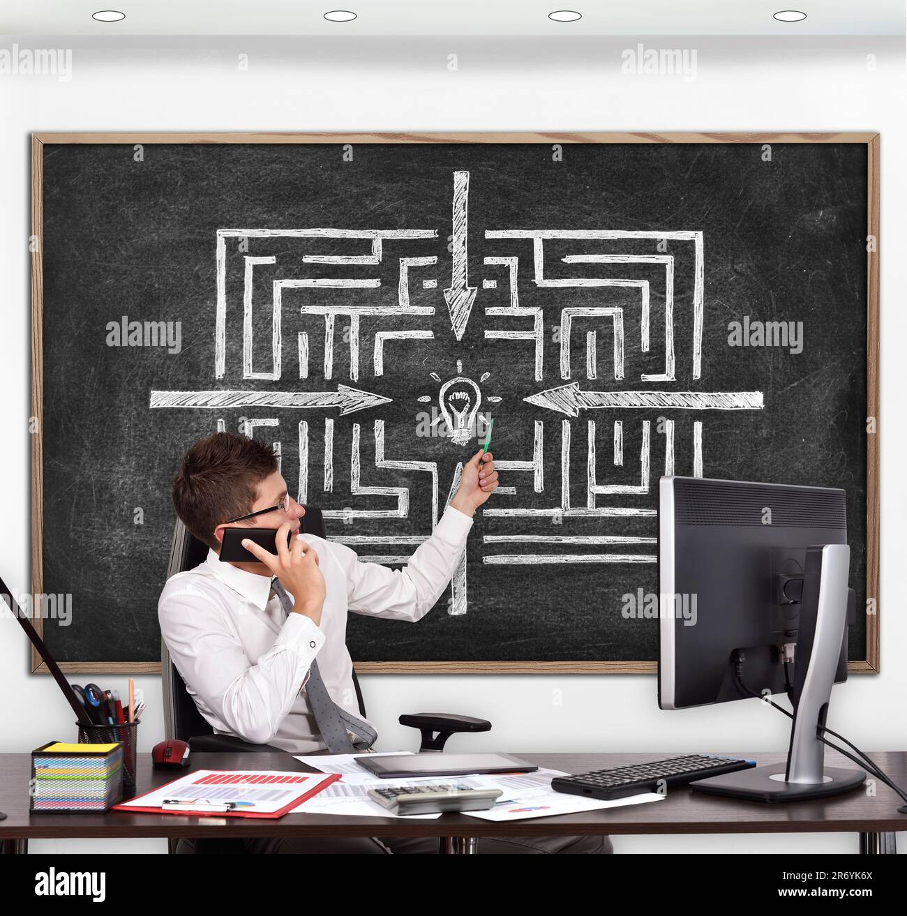 Ein Geschäftsmann im Zimmer zeigte auf eine Tafel mit einem Labyrinth Stockfoto