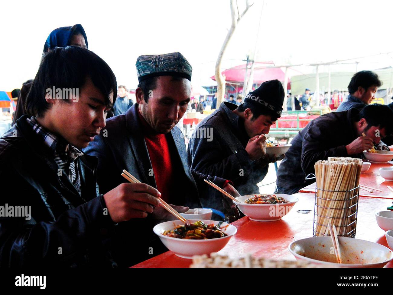 Ein kleines Straßenrestaurant, das Lagman-Nudeln und Reis mit Teigtaschen auf einem wöchentlichen Viehmarkt in den Außenbezirken von Kashgar, Xinjiang, China, serviert. Stockfoto