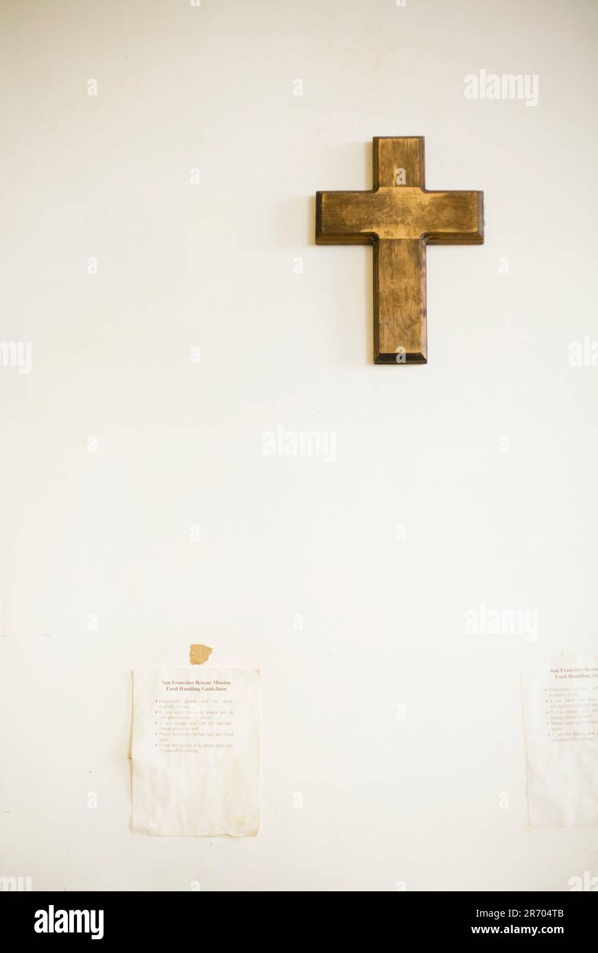 Ein Holzkreuz hängt an einer weißen Wand. Stockfoto