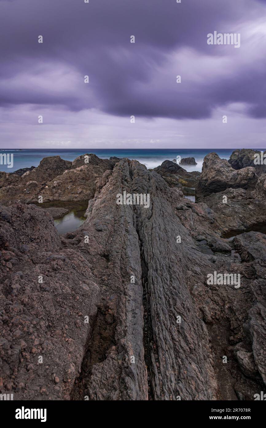Vulkanische Formation an der Küste, mit dunklen Regenwolken über dem Atlantischen Ozean, Puerto de la Cruz, Teneriffa, Kanarische Inseln Stockfoto