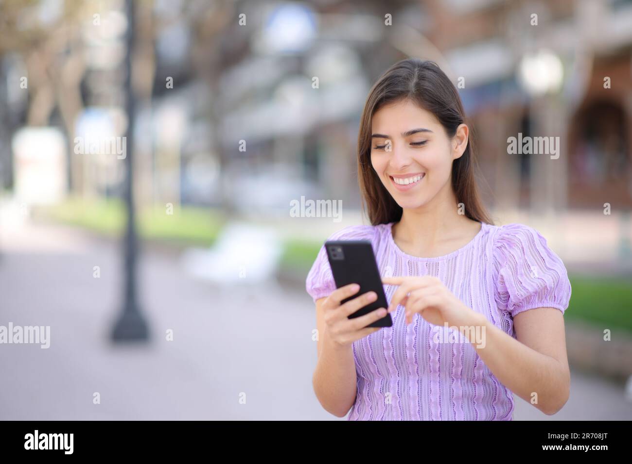 Glückliche Person, die mit dem Handy auf der Straße unterwegs ist Stockfoto