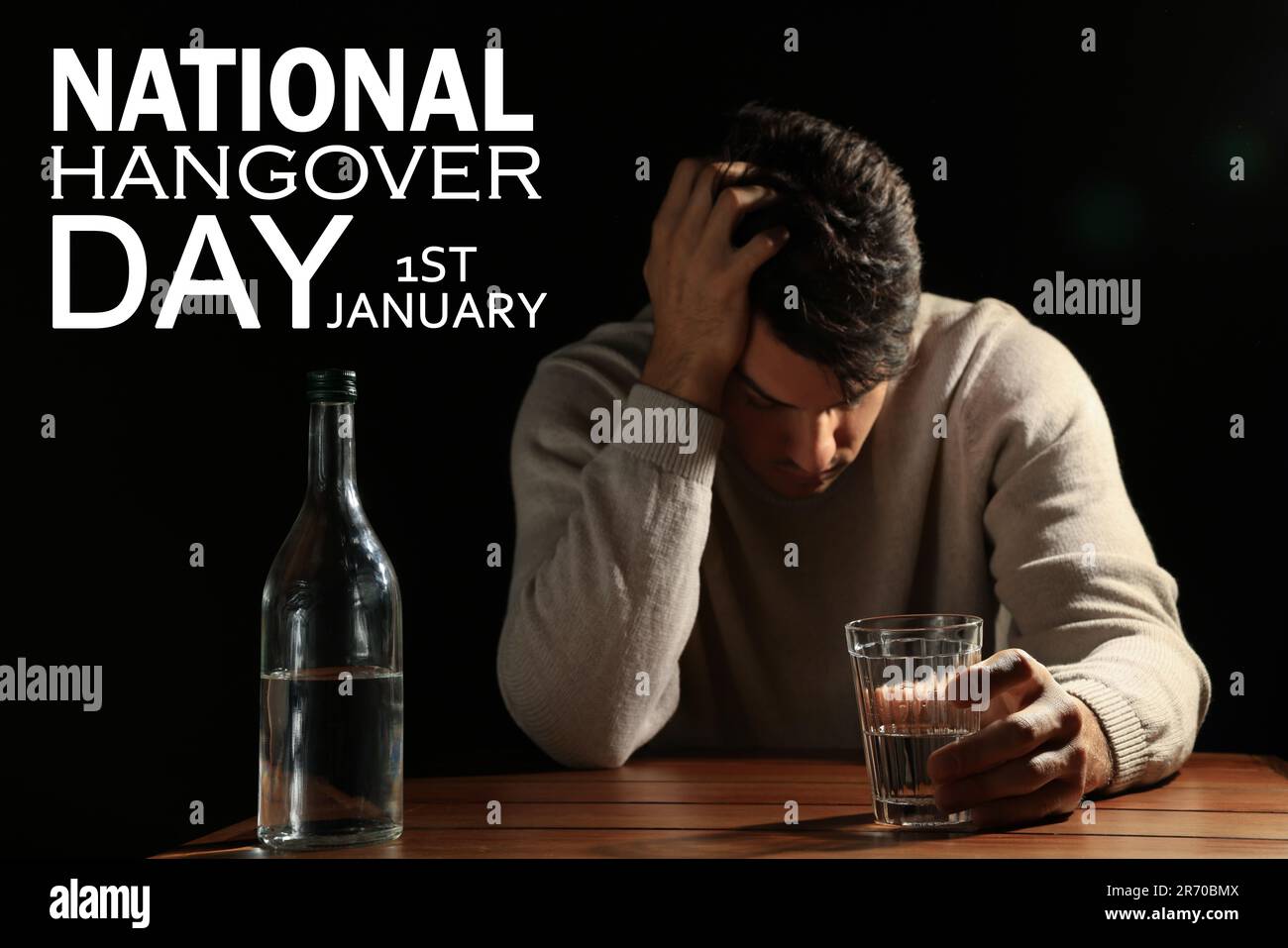 Nationaler Kater-Tag - 1. Januar. Mann mit alkoholischem Getränk am Tisch vor schwarzem Hintergrund Stockfoto