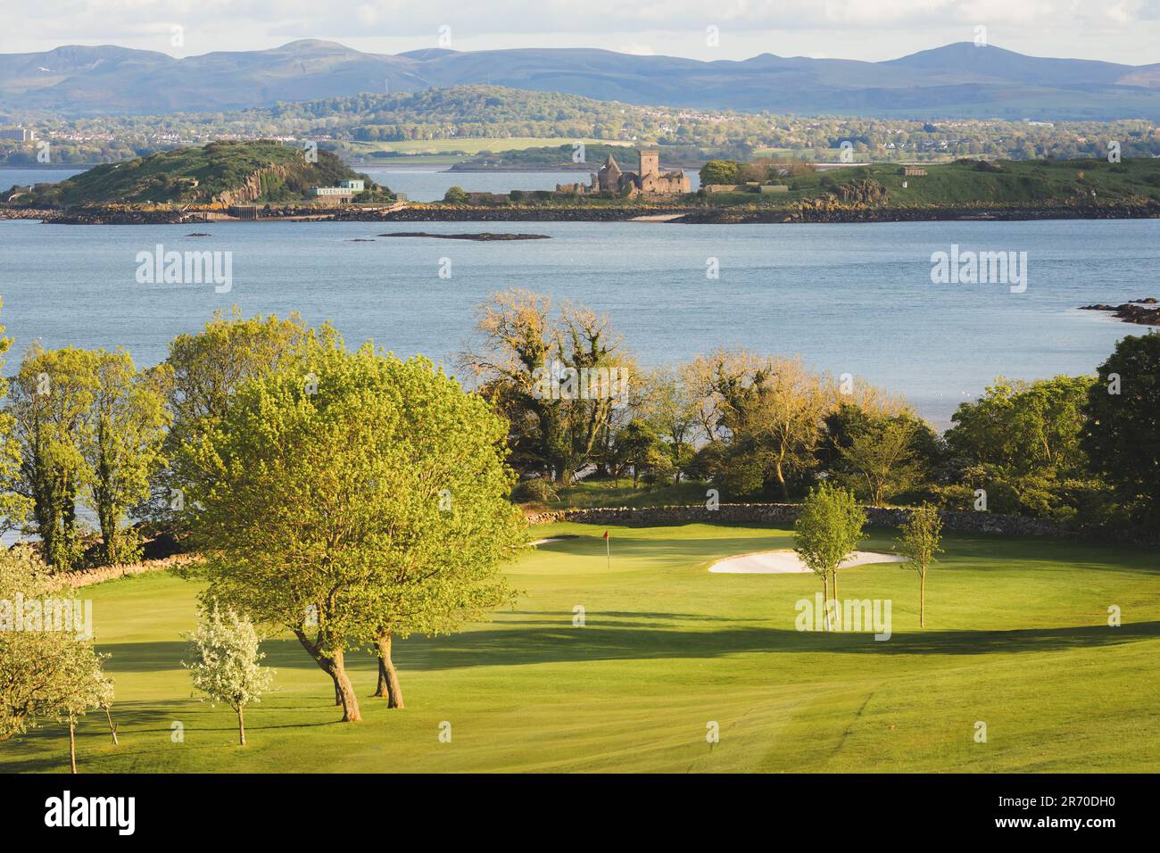 Malerischer Blick auf das Golfloch und das Grün an der Küste und den Firth of Forth mit der historischen Inchcolm Abbey und den Pentland Hills von Fife, Schottland Stockfoto