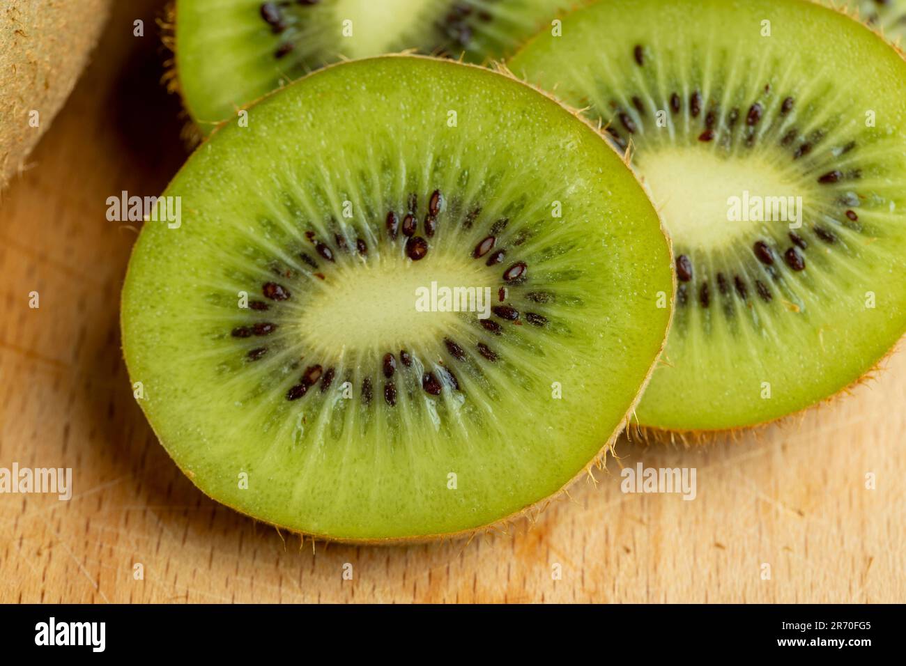 Eine Gruppe geschnittener grüner Kiwifrüchte mit schwarzen Samen, Details von in Stücke geschnittenem grünem Kiwipulp Stockfoto