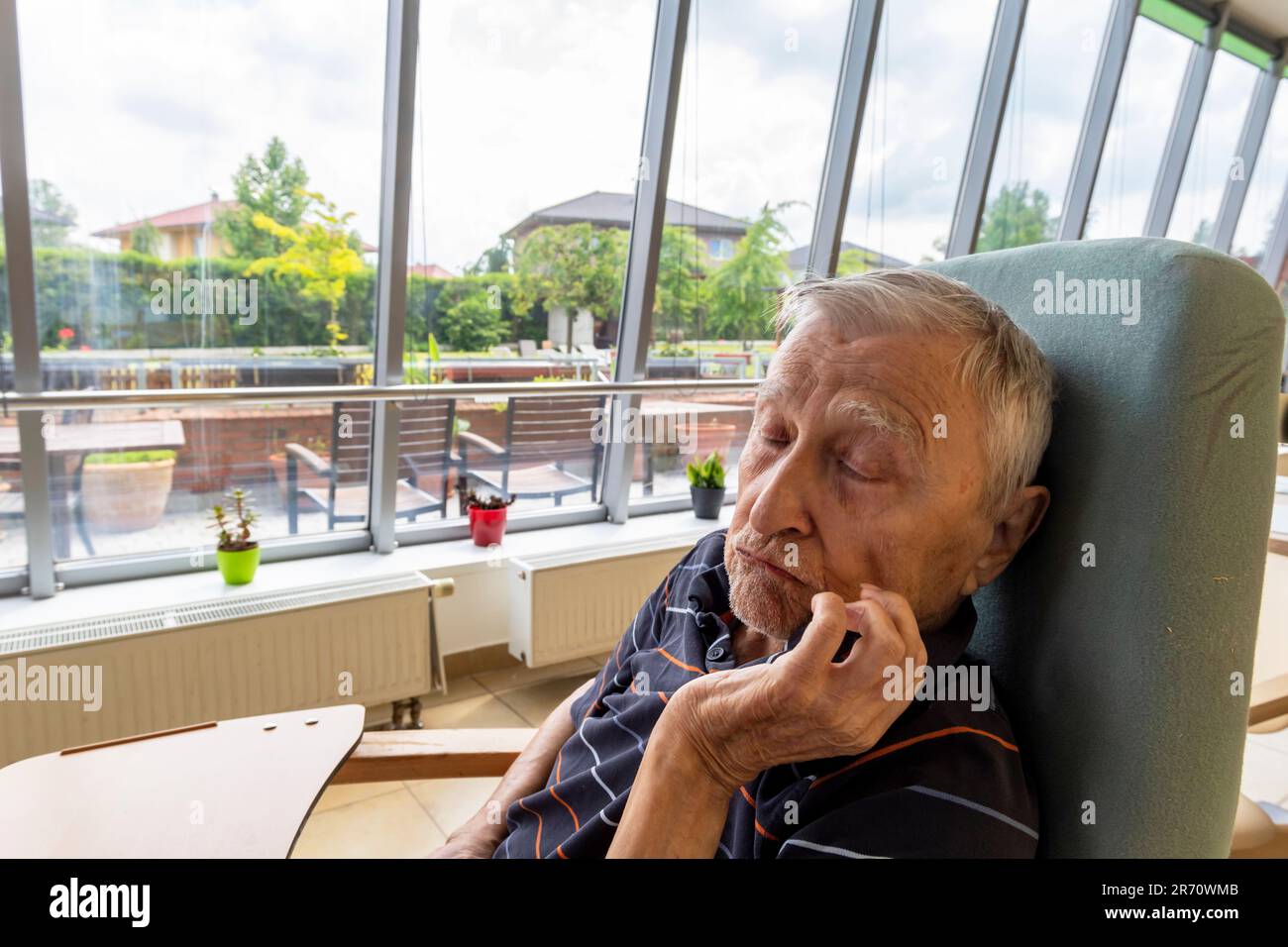 Altersrentner sitzt am Tisch im Altersheim Stockfoto