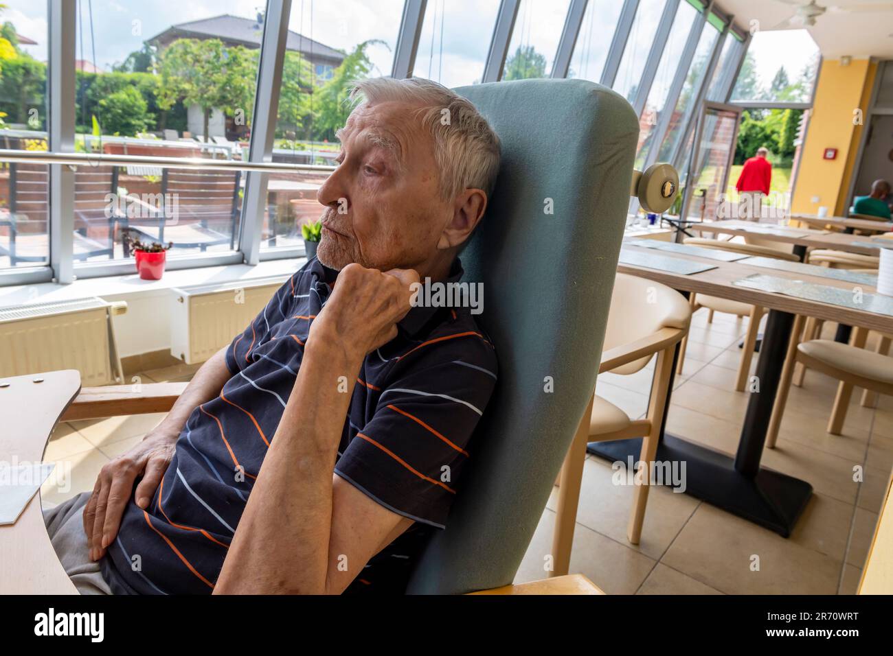 Altersrentner sitzt am Tisch im Altersheim Stockfoto