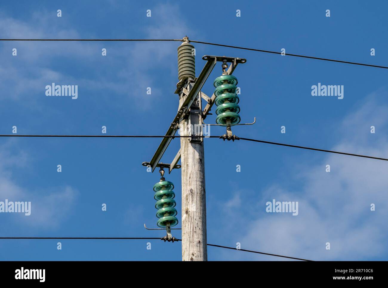 Hölzerne Strommasten mit Glasisolatoren zwischen den Kabeln. UK Stockfoto
