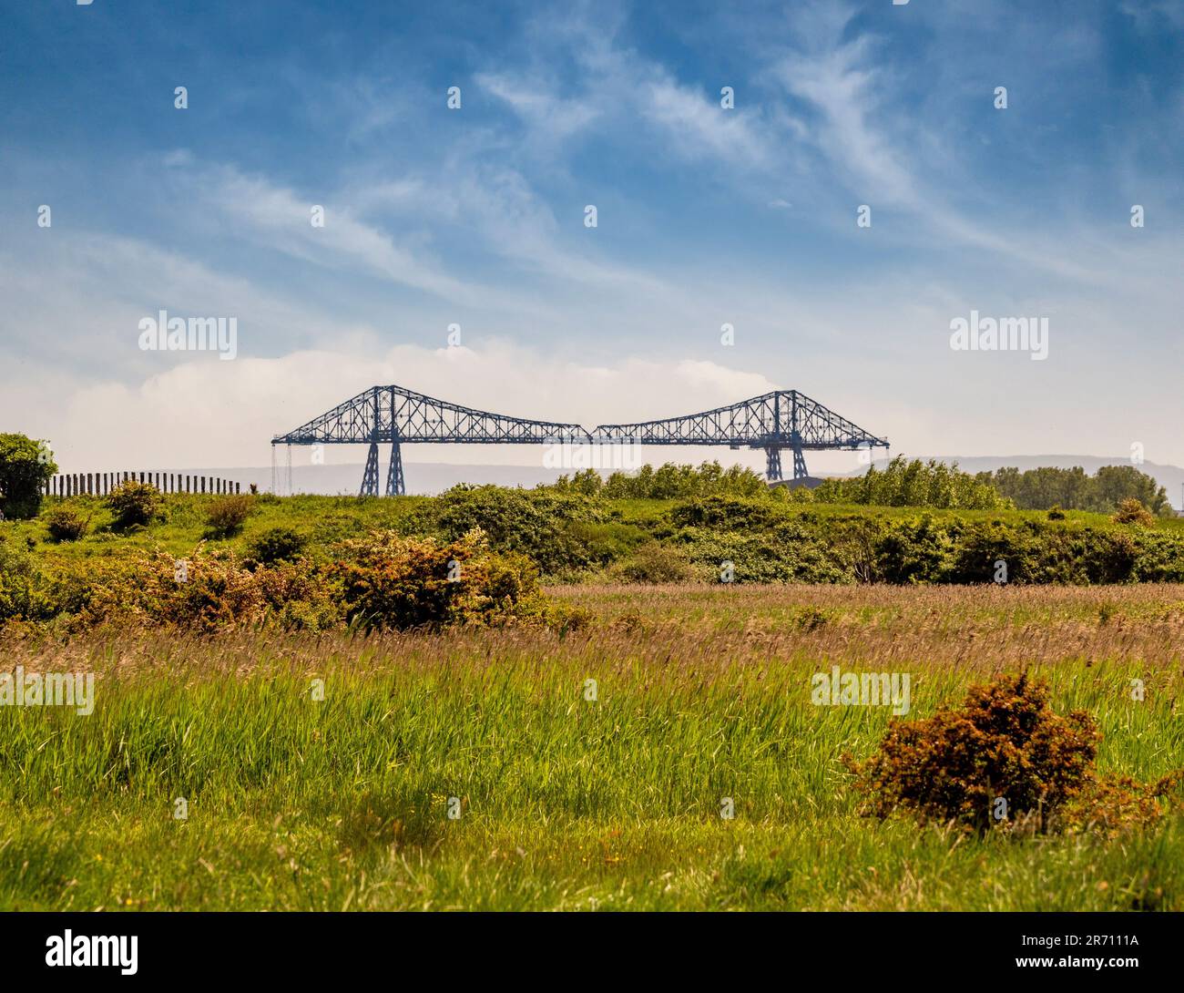 Blick nach Süden über das Grasland des Saltholme Naturschutzgebiets in Richtung der berühmten Middlesbrough Transporter Bridge, die den Fluss Tees umfasst. UK Stockfoto