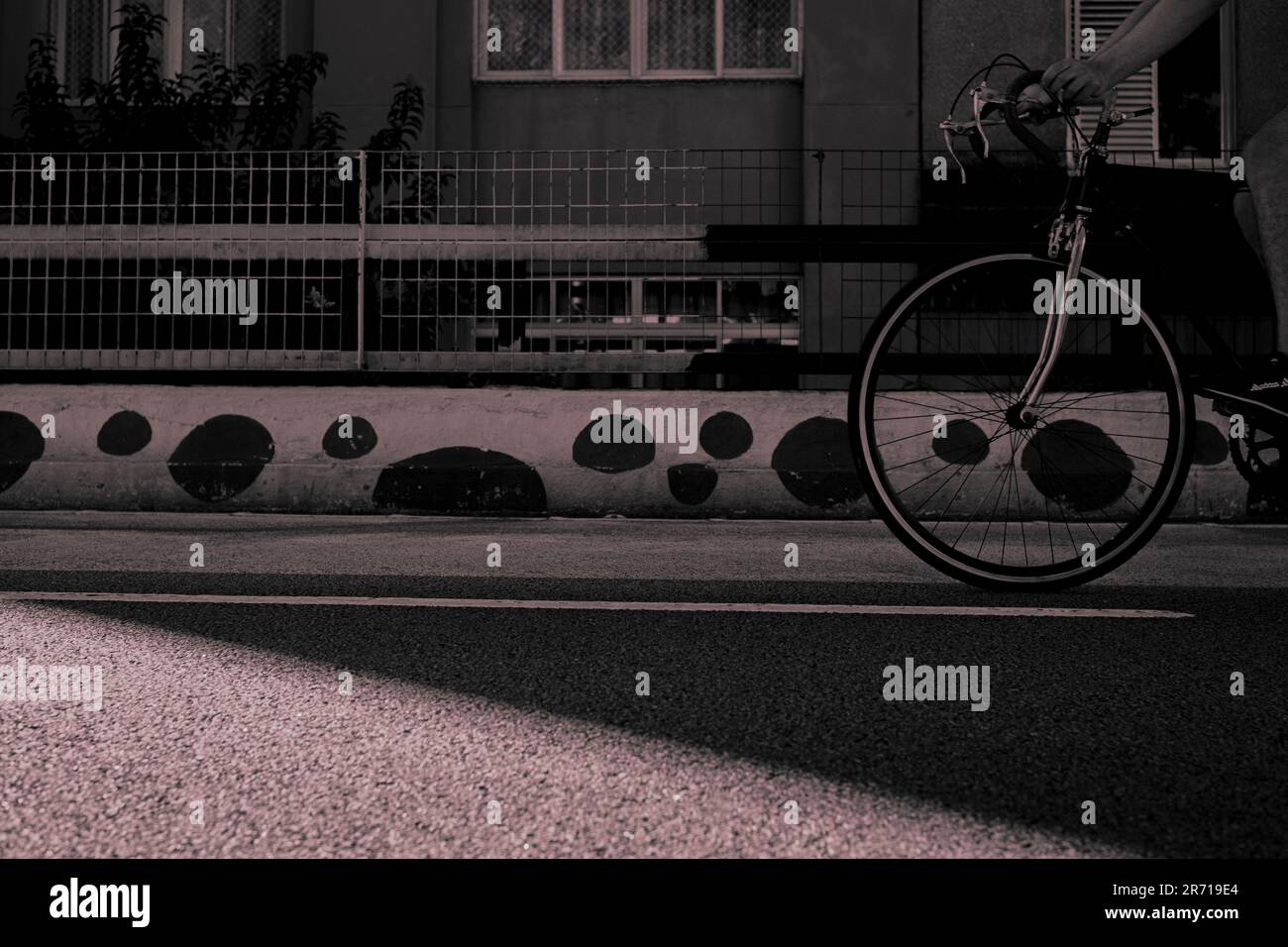Zeitlose Reise: Fahrrad gleitet links auf einem leeren Minhocão, die Silhouette des Vintage-Gebäudes, Sonnenlicht streichelt den Diagonal-Asphalt Stockfoto