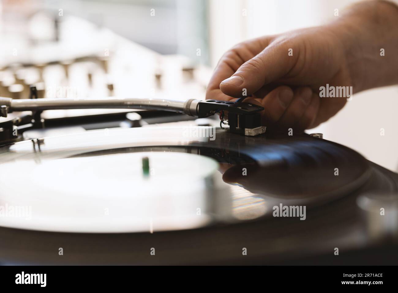 DJ-Hand stellt Nadel auf Vinylplatten ein. Mitten im Bild Stockfoto