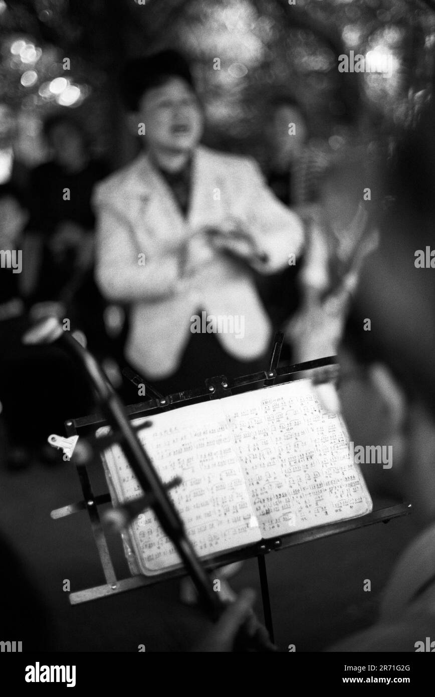 Shanghai China 2000. Im Fuxing Park treffen sich eine Gruppe von Freunden, um traditionelle chinesische Musik zu singen und zu spielen. Hier ist der erhu, eine zweireihige Geige, bei der der Bogen gegen den inneren Rand der Saiten und nicht gegen den äußeren wie bei einer Geige spielt. Die chinesische Musiknotation ist ein numerisches System, aber immer mehr westliche Notation und Musik werden übernommen. 2000s HOMER SYKES Stockfoto