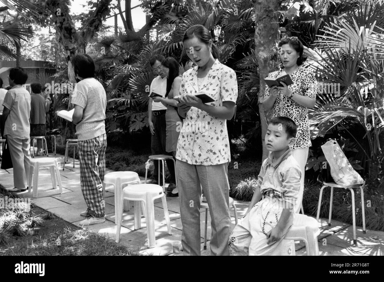 Shanghai China 2000. Die Shanghai Community Church in Hengshan Lu begrüßt seit ihrer Eröffnung im Jahr 1925 alle Mitglieder des christlichen Glaubens. Es gibt zwei Sonntagsdienste, beide ziehen eine große Gemeinde an, in der Überlaufräume voll belegt sind. Dank der geschlossenen Fernsehbildschirme kann die überströmte Gemeinde am Gottesdienst teilnehmen, während andere Mitglieder der Gemeinde es vorziehen, in den weitläufigen Gärten zu beten. 2000s HOMER SYKES Stockfoto