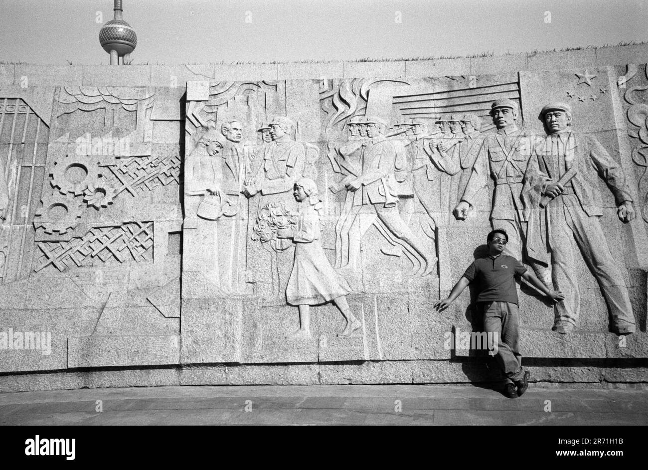 Shanghai China 2000. Das Denkmal für die Helden der Völker in den Huangpu-Gärten wurde am 31. Dezember 1988 begonnen und am 27. Mai 1994, dem 45. Jahrestag der Befreiung Shanghais, fertiggestellt. Ein dreiteiliger Betonpylon erhebt sich aus einer versunkenen Arena, in der sich ein 120 Meter langer Fries befindet. In sieben Abteilungen gegliedert, erinnert sie an die Kämpfe der Menschen zwischen 1840 und 1949. Hier im letzten Panel begrüßen die Menschen von Shanghai die Volksbefreiungsarmee, die PLA. Dies ist eine beliebte Gegend für Fußball und Sonnenbaden. 2000er Jahre HOMER SYKES Stockfoto