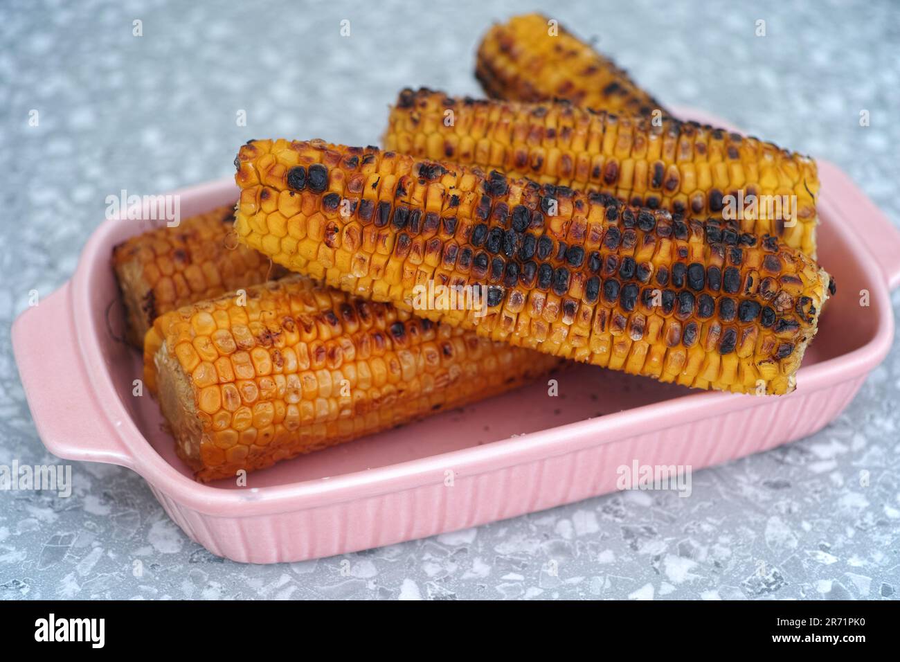 Geröstete Maiskolben in einem rosa Tablett. Schließen. Stockfoto