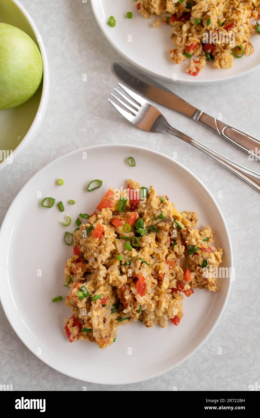 Gebratener brauner Reis mit Rühreiern, Thunfisch und Gemüse auf Tellern mit weißem Tischhintergrund Stockfoto