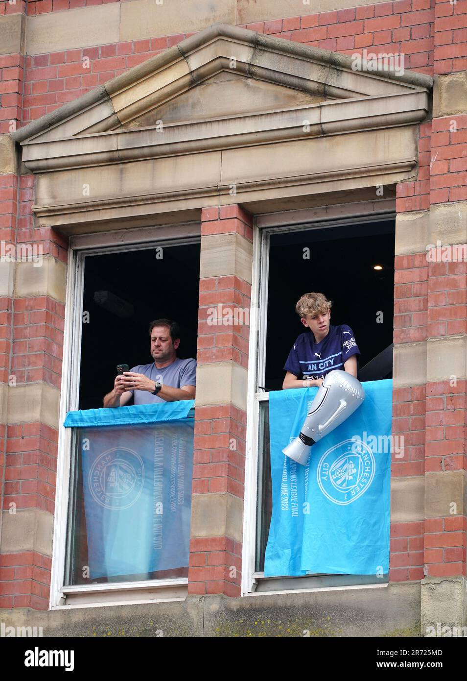 Fans, die vor der Treble Parade in Manchester aus dem Fenster schauen. Manchester City schloss die Treble (Champions League, Premier League und FA Cup) nach einem Sieg von 1-0 über Inter Mailand in Istanbul und sicherte ihnen den Ruhm der Champions League. Foto: Montag, 12. Juni 2023. Stockfoto