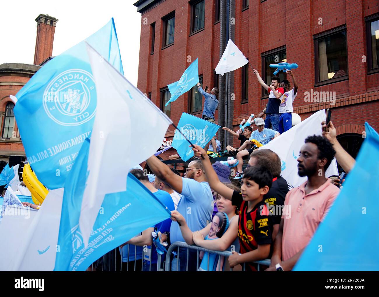 Fans, die vor der Treble Parade in Manchester mit der Flagge wedeln. Manchester City schloss die Treble (Champions League, Premier League und FA Cup) nach einem Sieg von 1-0 über Inter Mailand in Istanbul und sicherte ihnen den Ruhm der Champions League. Foto: Montag, 12. Juni 2023. Stockfoto