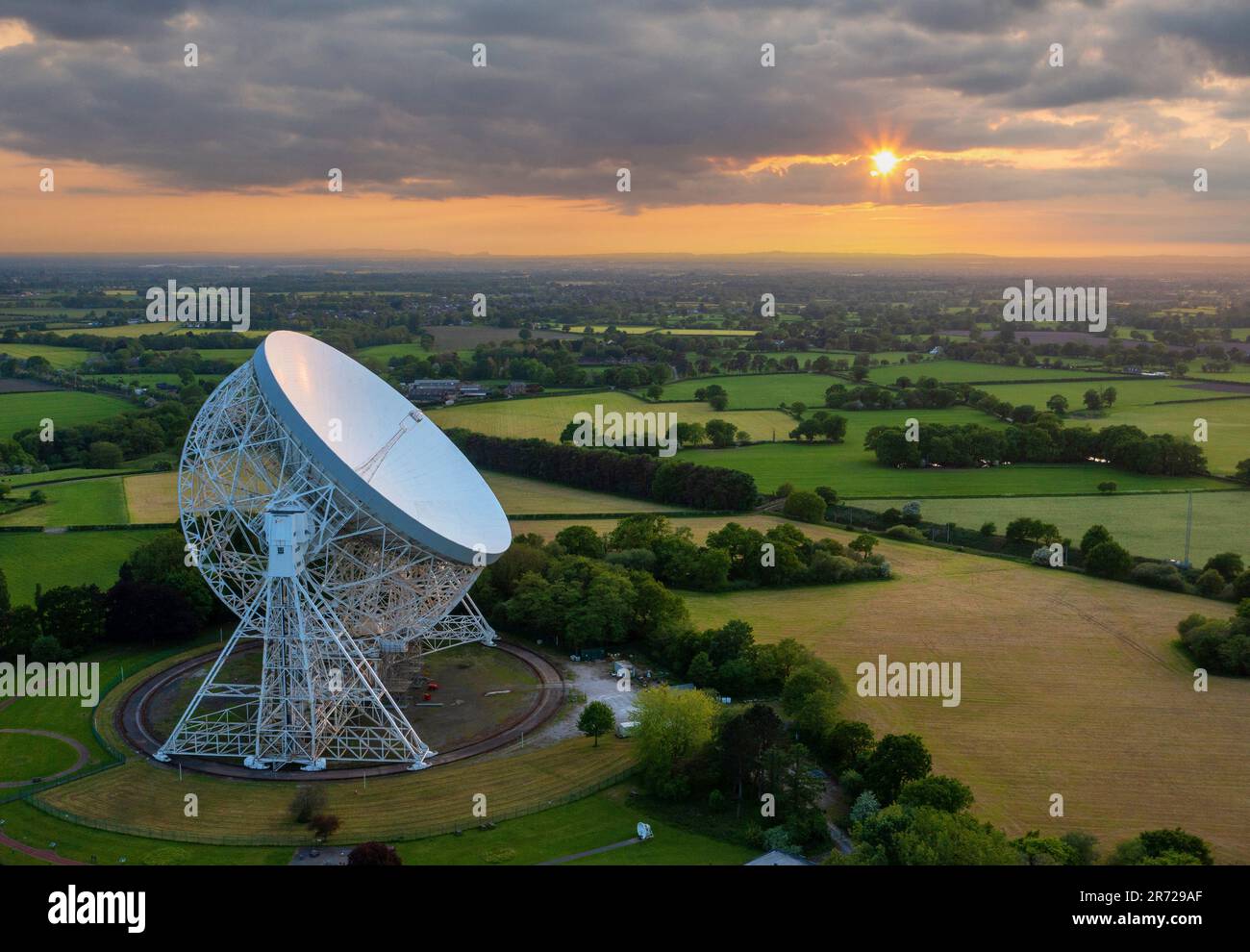 Goostrey, Cheshire, Vereinigtes Königreich. Der Sonnenuntergang spiegelt sich vor dem Lovell Telescope in der Jodrell Bank, Cheshire, wider. Luftbild. 22. Mai 2023 Stockfoto