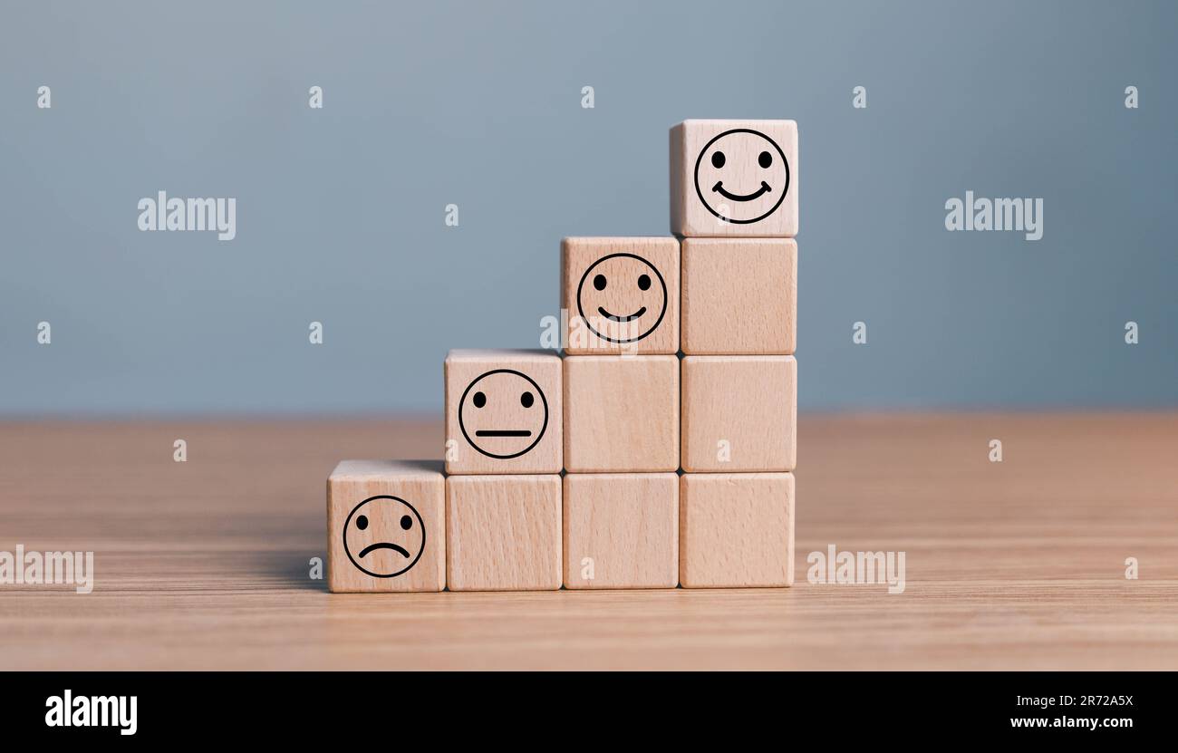 Lächeln Sie das Gesicht auf der positiven Seite und das traurige Gesicht auf der dunklen Seite auf einem Holzwürfel für ein positives Auswahlkonzept. Stockfoto