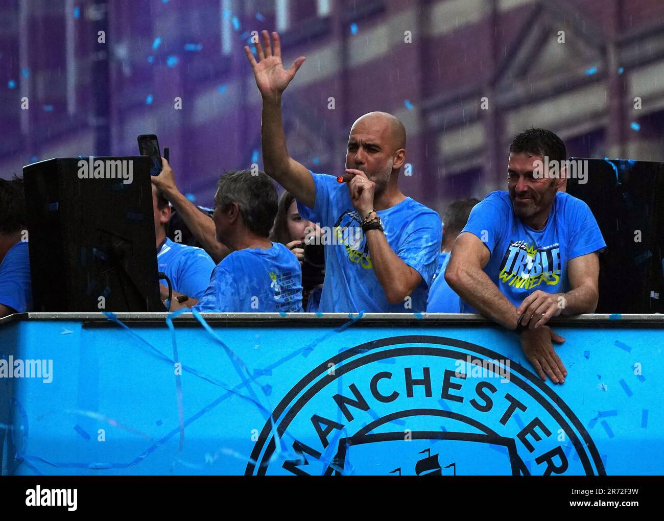 Manchester City Manager Pep Guardiola (links) raucht während der Treble Parade in Manchester neben dem Torhüter Xabier Mancisidor eine Zigarre. Manchester City schloss die Treble (Champions League, Premier League und FA Cup) nach einem Sieg von 1-0 über Inter Mailand in Istanbul und sicherte ihnen den Ruhm der Champions League. Foto: Montag, 12. Juni 2023. Stockfoto