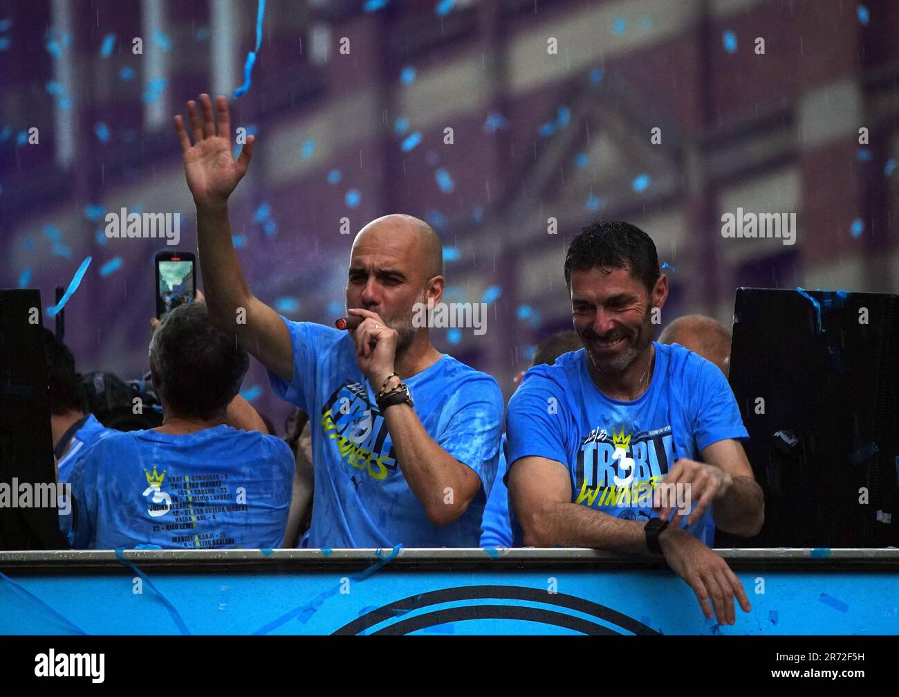 Manchester City Manager Pep Guardiola (links) raucht während der Treble Parade in Manchester neben dem Torhüter Xabier Mancisidor eine Zigarre. Manchester City schloss die Treble (Champions League, Premier League und FA Cup) nach einem Sieg von 1-0 über Inter Mailand in Istanbul und sicherte ihnen den Ruhm der Champions League. Foto: Montag, 12. Juni 2023. Stockfoto
