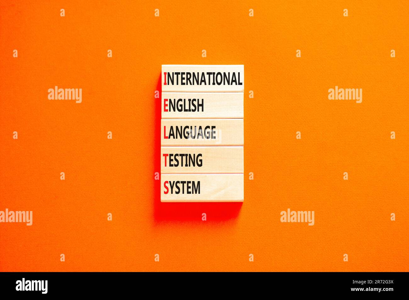 IELTS-Symbol. Konzeptbegriffe IELTS internationales englischsprachiges Prüfsystem auf Holzblock. Wunderschöner orangefarbener Hintergrund. Business IELTS internati Stockfoto