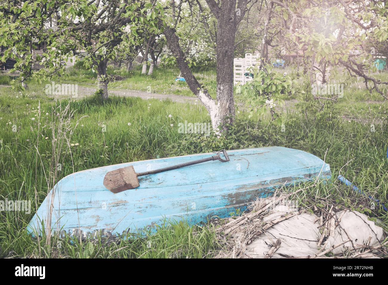 Ein altes Boot, das unter einem Baum abgelegt wurde, selektiver Fokus, Farbtönung angewendet. Stockfoto