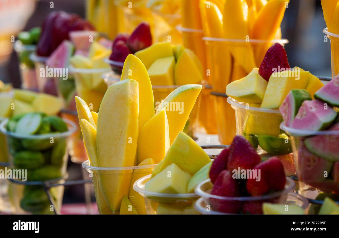 Nahaufnahme von gehackten, bunten, frischen tropischen Früchten in Bechern zum Verkauf auf dem lokalen Straßenmarkt in Vietnam. Stockfoto