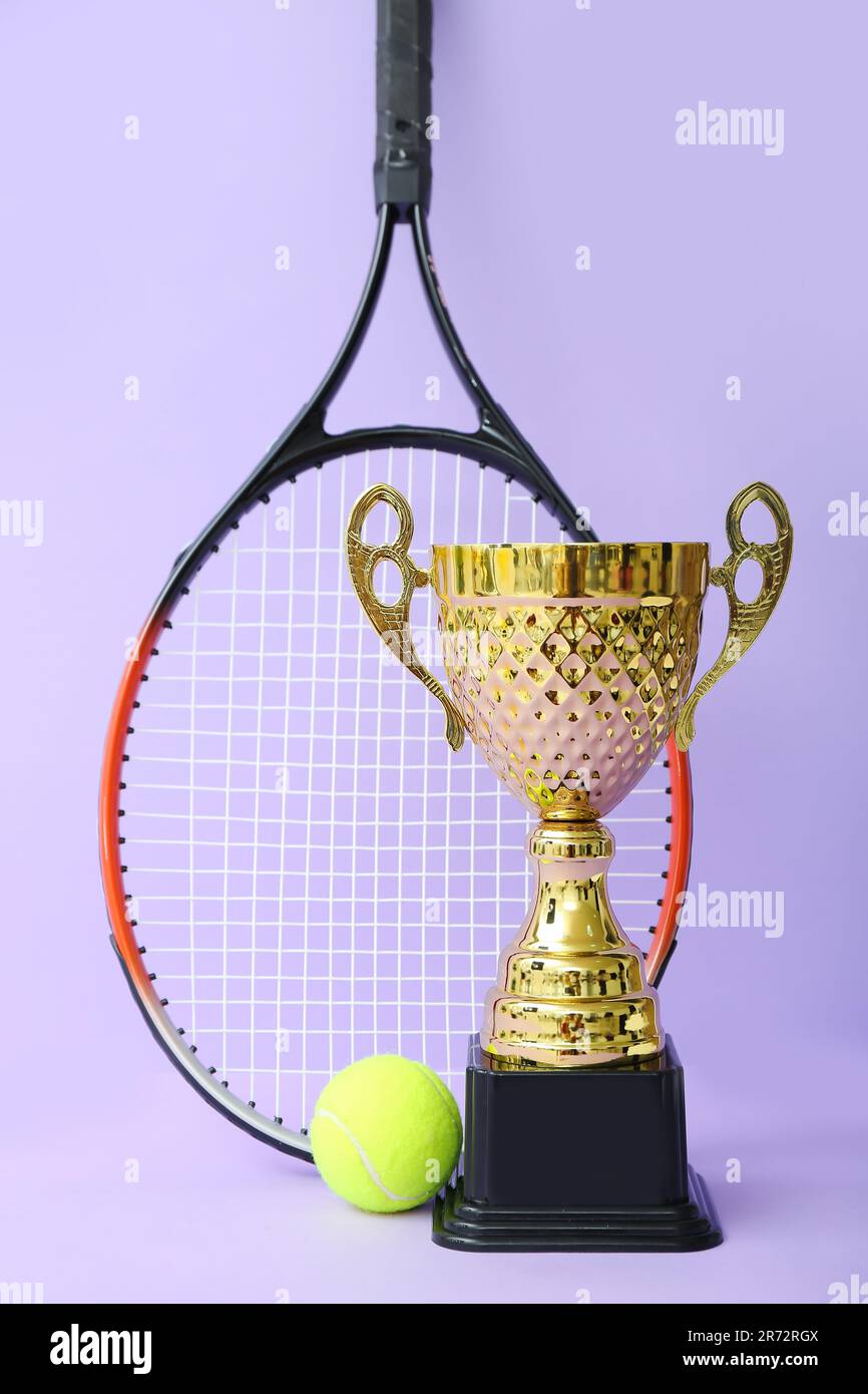 Goldene Tasse mit Tennisschläger und Ball auf lila Hintergrund  Stockfotografie - Alamy