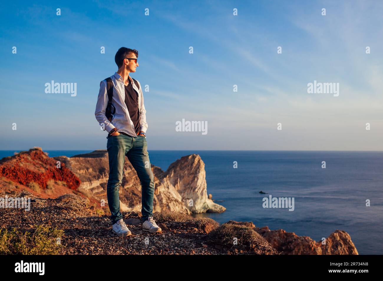 Wandern Sie am weißen Strand auf Santorini Insel Griechenland und genießen Sie die Meeresberglandschaft. Mann, der Rucksacktourist ist. Sommerferien Stockfoto Wandern Sie am weißen Strand auf Santorini Insel Griechenland und genießen Sie die Meeresberglandschaft. Mann, der Rucksacktourist ist. Sommerferien Stockfoto