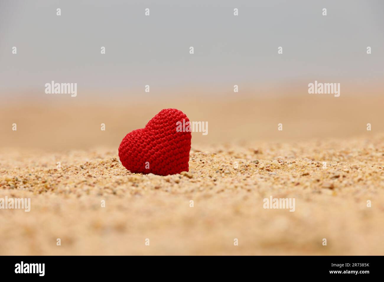 Rotes Strickherz auf einem Strand-Sand. Valentinstag, Konzept romantischer Reisen und Seereise Stockfoto