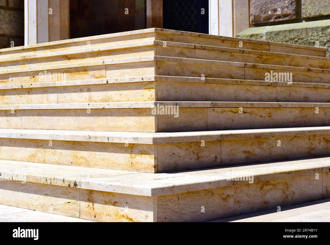 Beige Steintreppe außen. Abstrakte Nahaufnahme der Treppenecke. Steigung, Nase und Laufflächen. Außeneingang des Gebäudes. Steinsäulenbasis Stockfoto