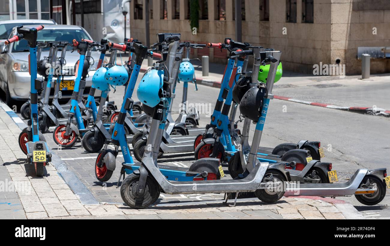 Gemeinsam genutzter Elektroroller reservierter Parkplatz, fotografiert in Tel Aviv, Israel, eine junge Frau nähert sich, um einen zu beanspruchen. Bei diesem Service handelt es sich um eine per Minute bezahlte usag Stockfoto