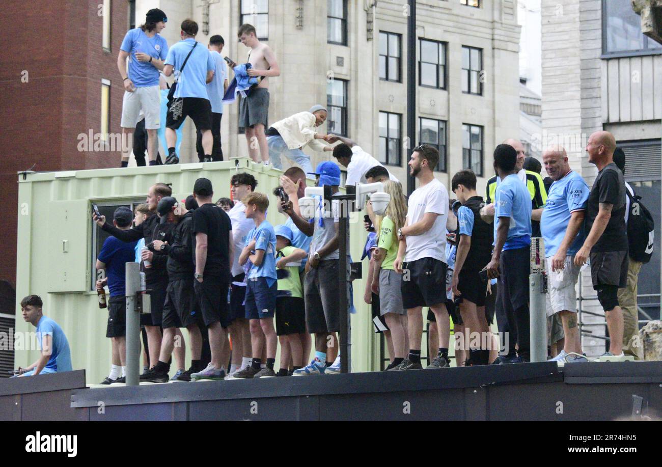 Manchester, Großbritannien. 12. Juni 2023. Die man City-Fans standen auf einer Baustelle und versuchten, die Siegesparade mit offenem Oberdeck im Zentrum von Manchester, Großbritannien, zu sehen, um die Erfolge ihres Clubs zu würdigen, der die Höhen gewonnen hat: Die Premier League, der FA Cup und die Champions League. Am Samstag besiegte man City Inter Mailand in Istanbul und sicherte sich den Champions League-Sieg. Die Parade der offenen Busse fuhr durch das Stadtzentrum von Manchester und beobachtete von großen, begeisterten Massen, trotz Gewitter und starkem Regen. Kredit: Terry Waller/Alamy Live News Stockfoto