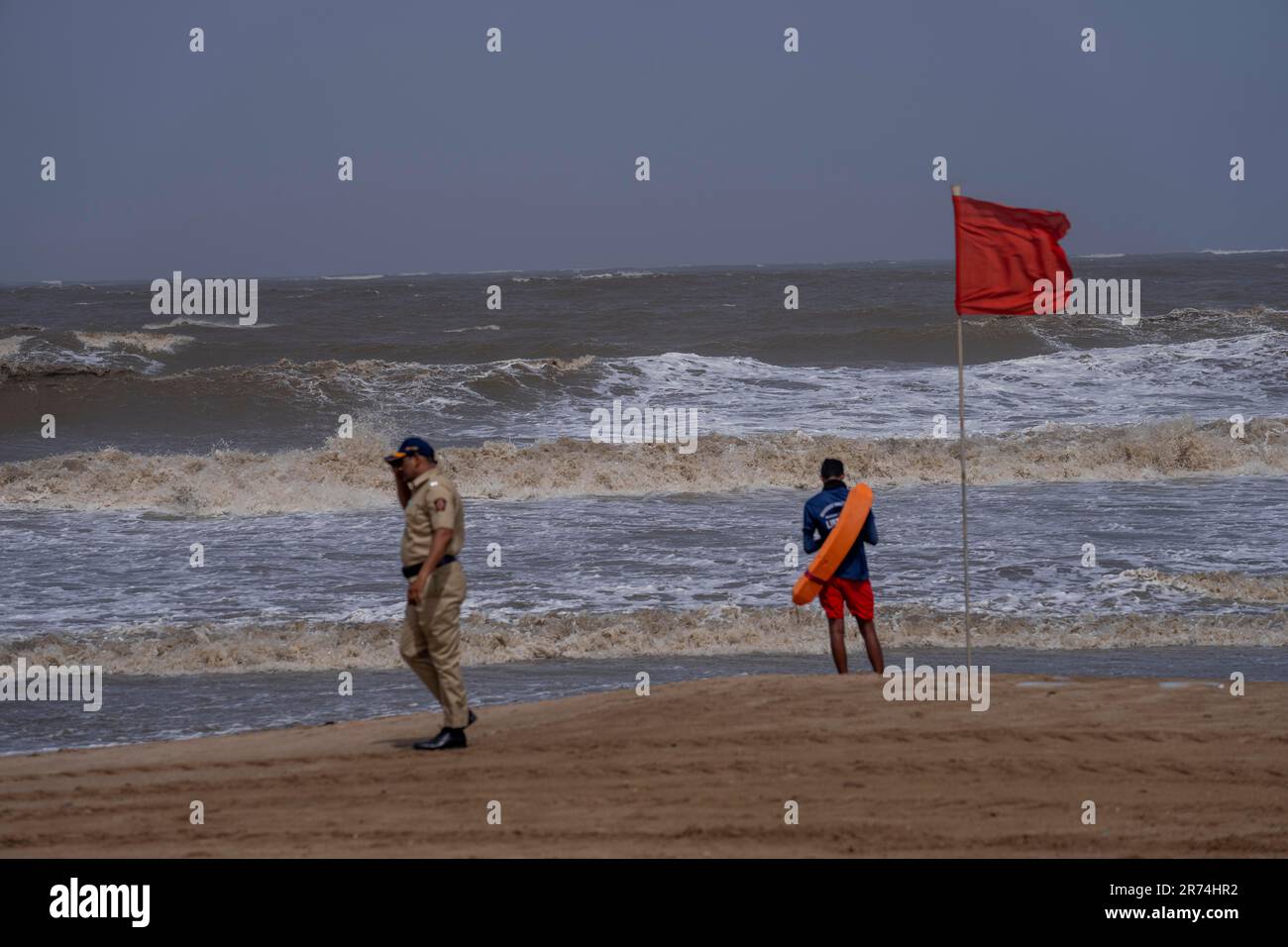 A police officer walks past a lifeguard standing guard during a high ...