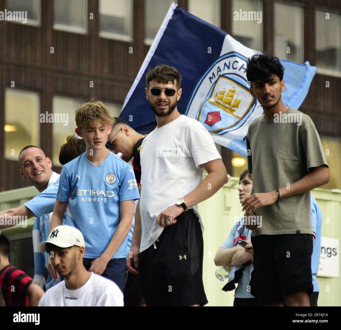 Manchester, Großbritannien. 12. Juni 2023.man City-Fans standen auf einer Baustelle, um die Siegesparade mit offenem Oberdeck im Zentrum von Manchester, Großbritannien, zu sehen, um die Erfolge ihres Clubs zu feiern, der die Höhen gewonnen hat: Die Premier League, der FA Cup und die Champions League. Am Samstag besiegte man City Inter Mailand in Istanbul und sicherte sich den Champions League-Sieg. Die Parade der offenen Busse fuhr durch das Stadtzentrum von Manchester und beobachtete von großen, begeisterten Massen, trotz Gewitter und starkem Regen. Kredit: Terry Waller/Alamy Live News Stockfoto