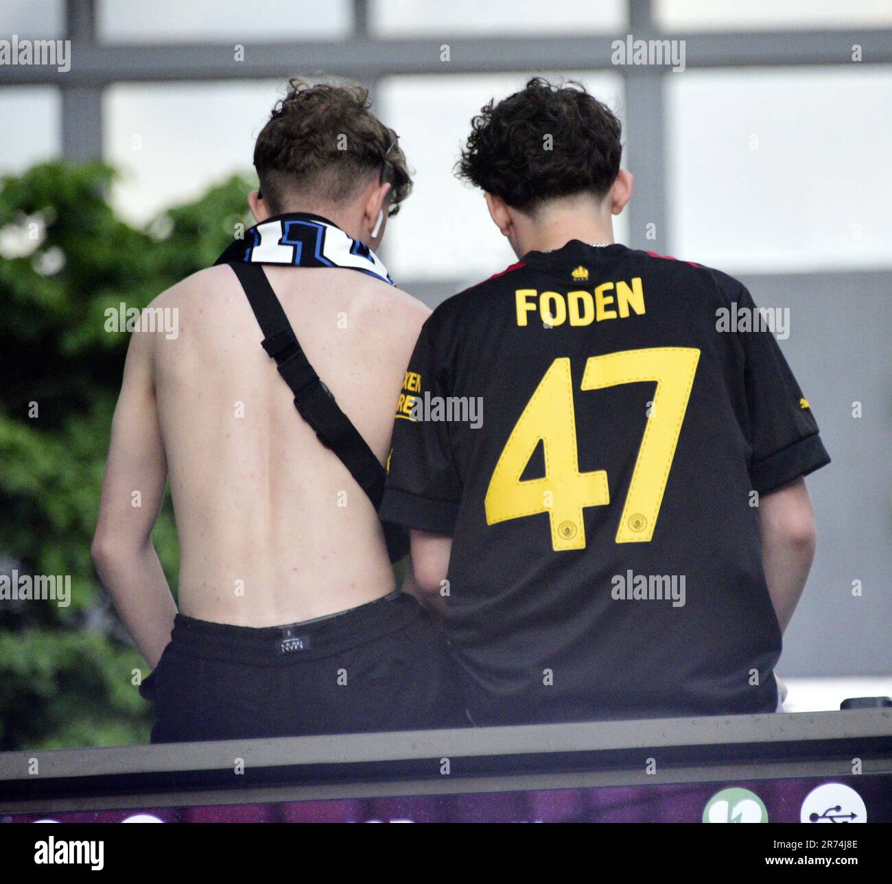 Manchester, Großbritannien. 12. Juni 2023. Die man City-Fans sitzen auf einer Werbetafel, um die Siegesparade im offenen Bus im Zentrum von Manchester, Großbritannien, zu sehen, die die Erfolge ihres Vereins zum Sieger der Höhen zeigt: Die Premier League, der FA Cup und die Champions League. Am Samstag besiegte man City Inter Mailand in Istanbul und sicherte sich den Champions League-Sieg. Die Parade der offenen Busse fuhr durch das Stadtzentrum von Manchester und beobachtete von großen, begeisterten Massen, trotz Gewitter und starkem Regen. Kredit: Terry Waller/Alamy Live News Stockfoto