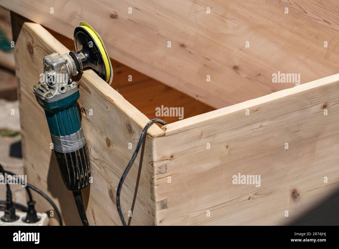 Holzkiste mit altem Winkelschleifer an sonnigen Tagen, Nahaufnahme zum Elektrowerkzeug am Brett Stockfoto